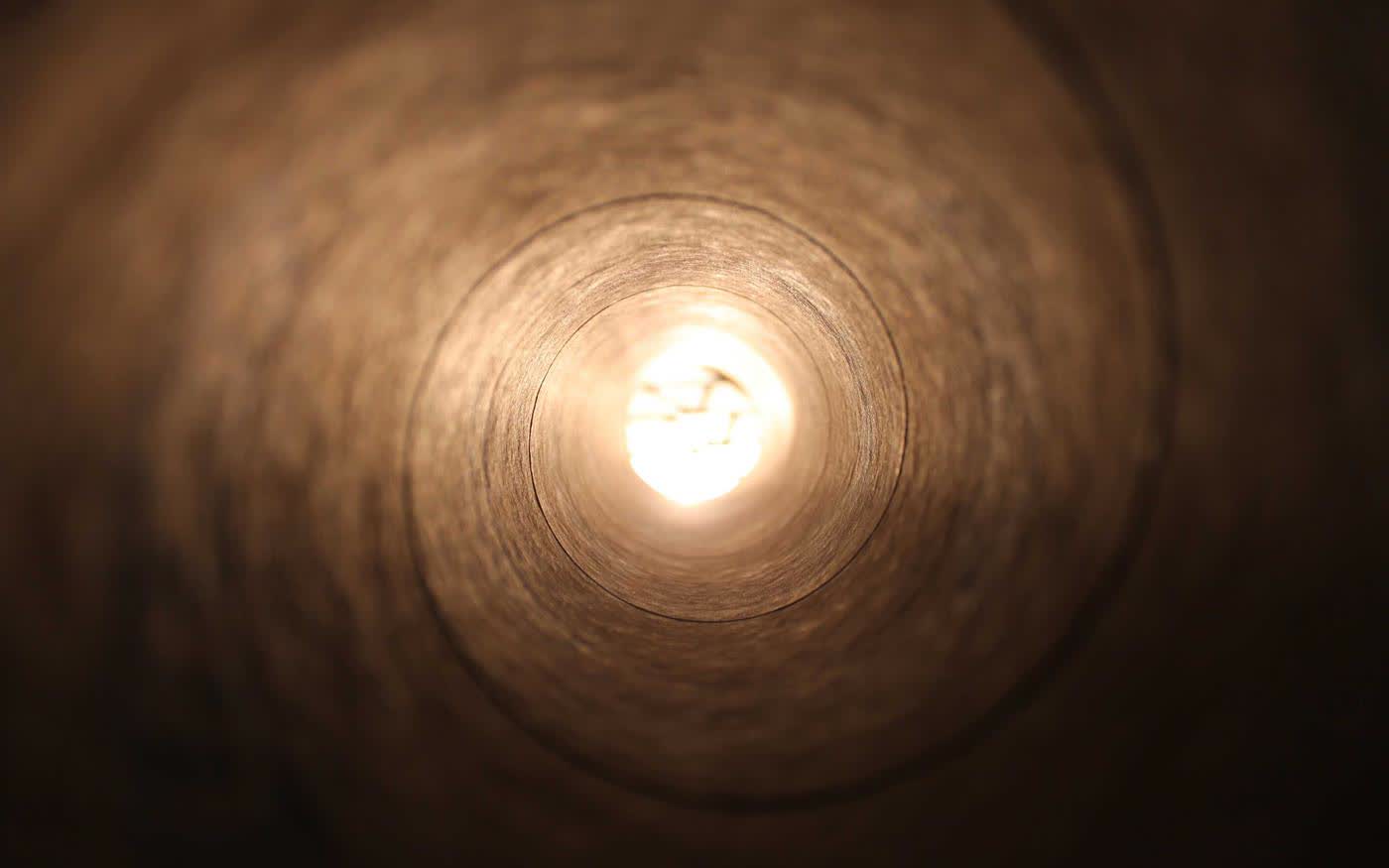 Looking up a deep circular shaft to a single distant point of daylight